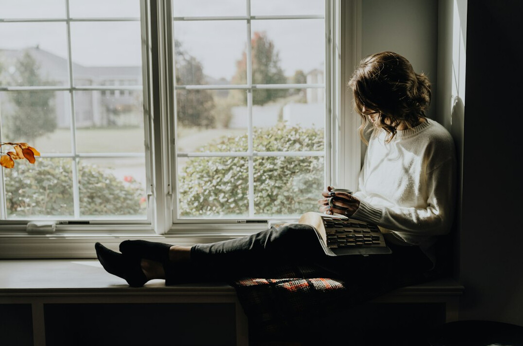 man reading book by window